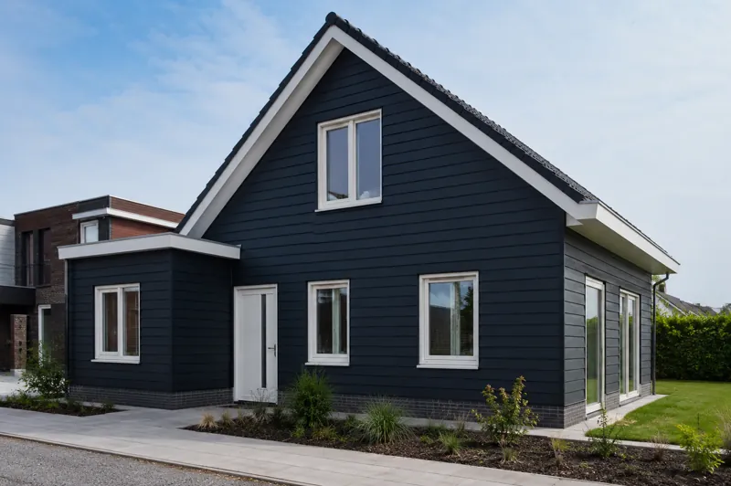 Woning met donkerblauw geschilderde gevelbekleding en witte kozijnen