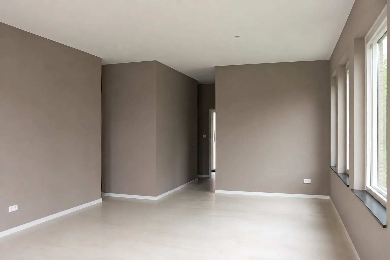 Strak afgewerkte wanden en plafond met witte plinten in een woning in Assen